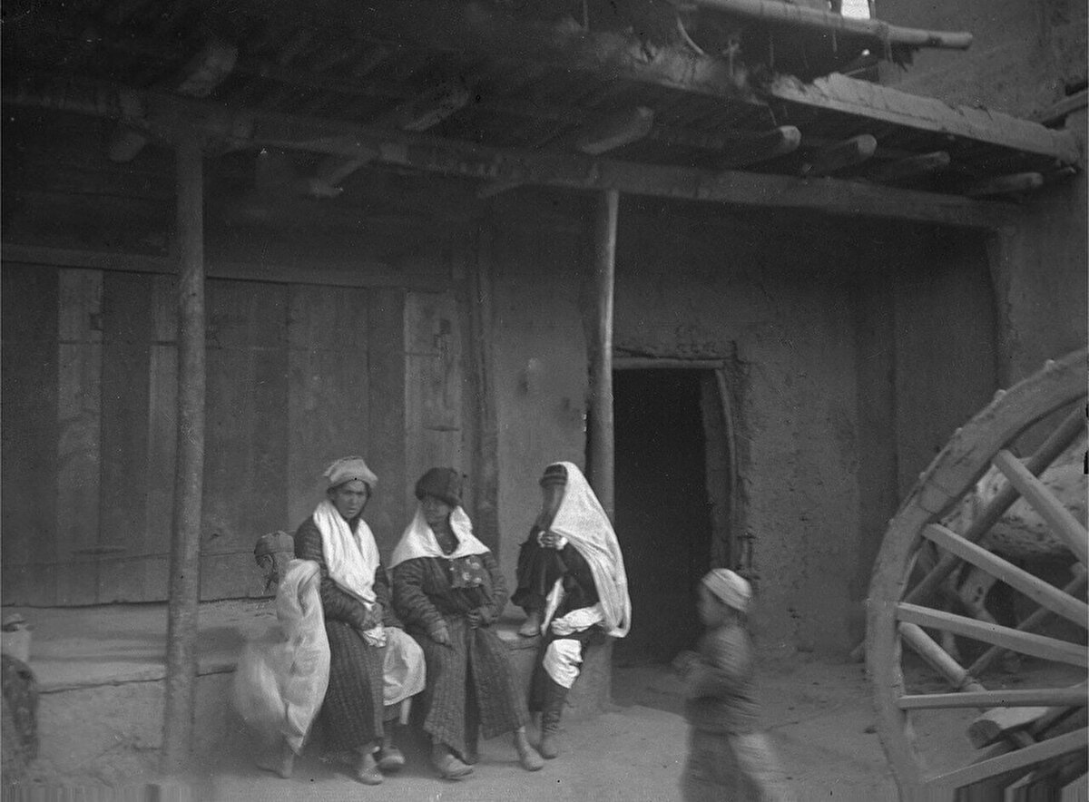 Geleneksel kıyafetli Uygur kadınlar ve çocuklar, ev önünde otururken. Aksu şehri, 1906-1908.