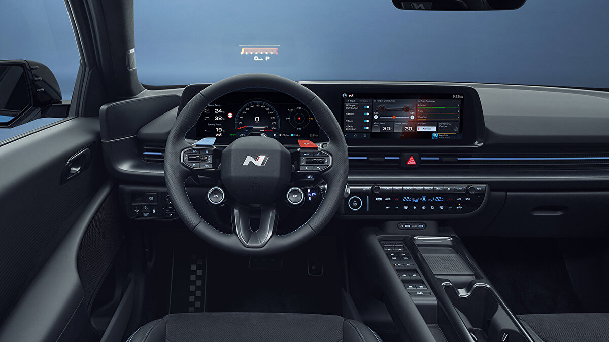 N direksiyon üzerindeki iki kısayol, güç aktarma ve şasi modlarını anında değiştiriyor. Dijital gösterge pist verilerini net gösteriyor; merkezi ekran ısı yönetimi ve ön koşullandırma seçeneklerine hızlı erişim veriyor.