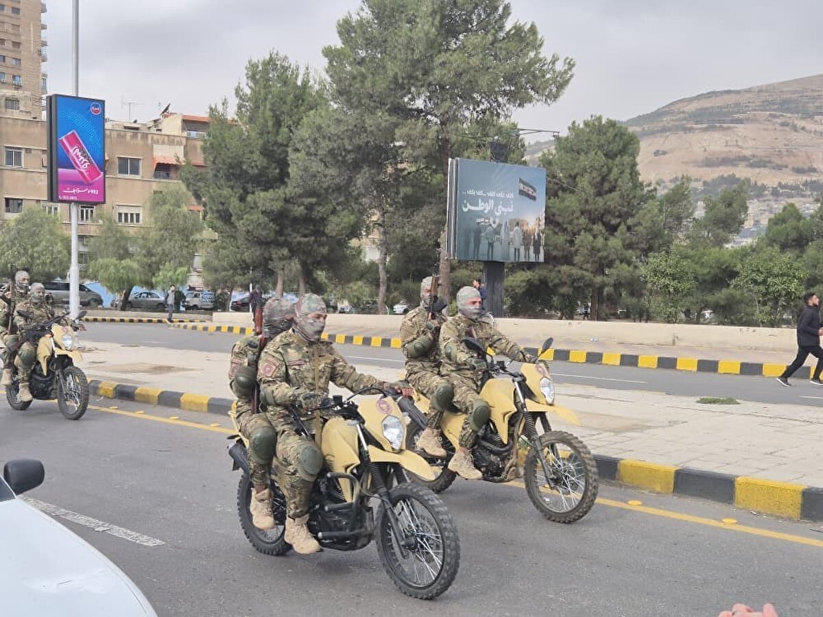 Yeni yönetimin Şam’daki ilk yıl dönümü etkinlikleri<br><br>Sabahın erken saatlerinde binlerce Suriyeli, Şam’ın simge yapılarından Emevi Camii’nde bir araya geldi. Suriye Devlet Başkanı Ahmed eş-Şara’nın camiye gelişi, kalabalık tarafından yoğun ilgiyle karşılandı. Direniş dönemindeki askeri üniformasını ilk kez törene taşıyan Eş-Şara, halkla birlikte yıl dönümü programına katıldı.