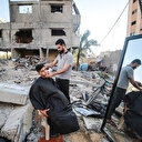 Gazzeli berber işgalci İsrail'in bombaladığı dükkanının enkazı üzerinde çalışmaya devam ediyor