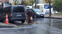 Yaşlı kadın bastonuyla yağmurda tıkanan mazgalı açtı