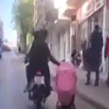 Motosiklette giderken bebek arabası çekiyor