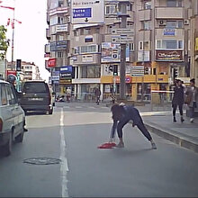 Yola düşen bayrağı araçlar üstünden geçmesin diye aldı