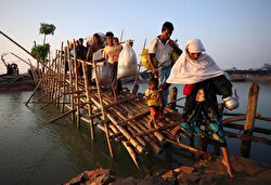 Rohingya refugees cross a bamboo bridge as they arrive at a port after crossing from Myanmar, in Teknaf, Bangladesh.