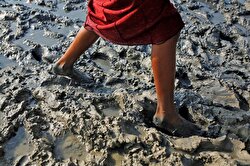 A Rohingya refugee girl walks in mud after crossing the Bangladesh-Myanmar border, at a port in Teknaf, Bangladesh.