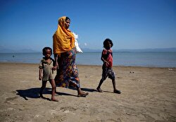 Rohingya refugees walk on the shore as they arrive on a makeshift boat after crossing the Bangladesh-Myanmar border, at Shah Porir Dwip near Cox's Bazar.