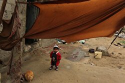 A child is seen along with a cat on a cold day in Khan Younis district of Gaza City, Gaza on January 05, 2018. Children of families, that live in makeshift tents, play around junk cars regardless of cold weather.