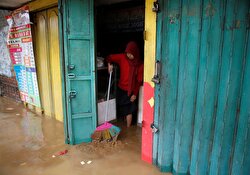 A woman cleans up her shop in flood hit Jatinegara district in Jakarta