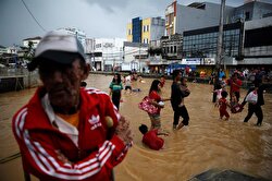 People wade through a flooded street in Jakarta