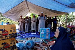 Villagers hold evening prayer inside a temporary shelter