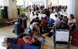 Foreign tourists sit and lie on the floor as they queue to leave Lombok Island
