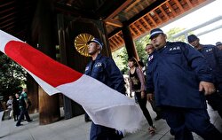Right wing group members in uniforms make their way with Japan's national flag as they visit Yasukuni Shrine 