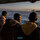 Libya kıyılarında tekneleri batmak üzereyken kurtarılan mülteciler, Sicilya’ya geri götürüldüğü esnada Messina kıyılarını izlerken. Umut, çaresizlik. (Santi Palacios/AP)