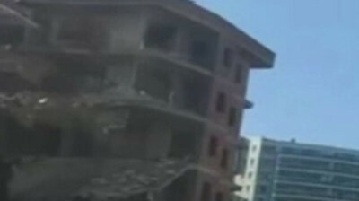 Building set for demolition collapses as bulldozer operator watches on