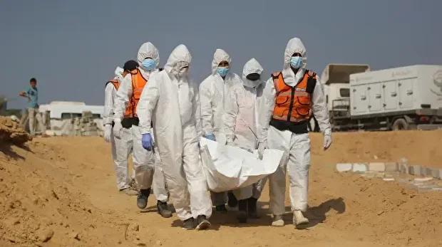 Des agents de santé et des travailleurs civils transportent les corps de Palestiniens pour un enterrement collectif dans un cimetière de Khan Yunis, dans le sud de la bande de Gaza, le 10 novembre 2025.