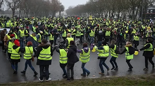 Des manifestants vêtus d'un gilet jaune dansent lors d'une manifestation antigouvernementale organisée par le mouvement des Gilets jaunes, à Bourges, le 12 janvier 2019. 