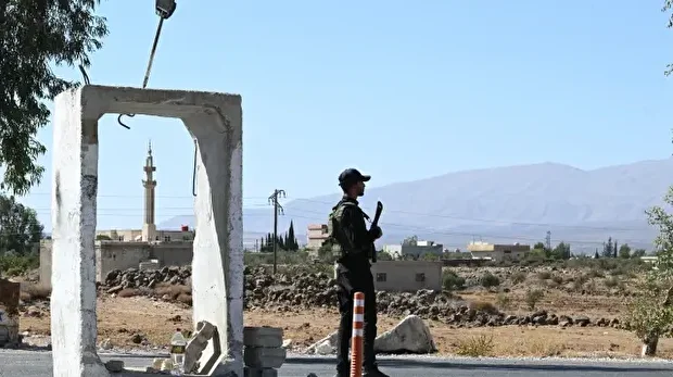 Un membre des forces de sécurité syriennes monte la garde devant une ancienne base militaire près de la ville de Quneitra, dans le sud de la Syrie, à la lisière du plateau du Golan annexé par Israël, le 21 septembre 2025.