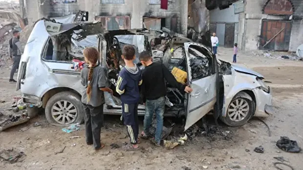 Des enfants palestiniens déplacés regardent un véhicule détruit par l'armée israélienne, à Gaza, le 22 novembre 2025. 