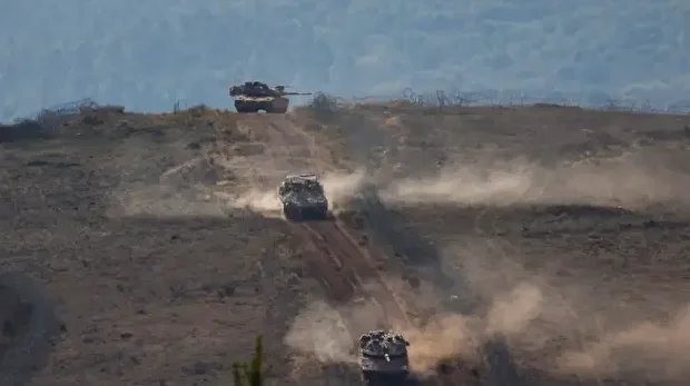 Des chars militaires israéliens patrouillent près d'un mur en béton le long de la barrière frontalière séparant le nord d'Israël du sud du Liban, le 24 novembre 2025.