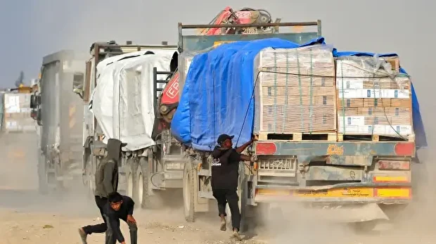 Un Palestinien déplacé tente de monter sur un camion circulant sur la route Salah al-Din dans le centre de la bande de Gaza, près de Deir al-Balah, alors que des personnes tentent d'obtenir de l'aide humanitaire, le 9 novembre 2025. 