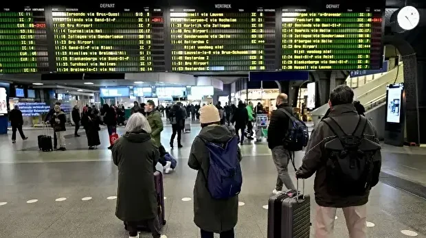 Des passagers consultent le tableau des départs à la gare du Midi - Zuidstation (Bruxelles-Sud) le premier jour d'une grève nationale de 72 heures organisée par les syndicats des transports publics ferroviaires, à Bruxelles, le 24 novembre 2025.
