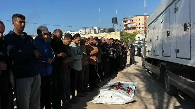 Des hommes récitent des prières funéraires près du corps d'un jeune homme, Mahmoud Abu Shab, enveloppé dans un linceul, à l'extérieur du complexe médical Nasser à Khan Yunis, dans la bande de Gaza, le 26 novembre 2025.