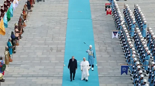 Cette photo prise et publiée par le service de presse de la présidence turque le 27 novembre 2025 montre le pape Léon XIV (à droite) et le président turc Recep Tayyip Erdogan (à gauche) passant les troupes en revue lors d'une cérémonie d'accueil à l'arrivée du pape pour une réunion au palais présidentiel d'Ankara.