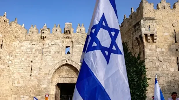 Des militants de droite se rassemblent avec des drapeaux israéliens devant la porte de Damas de la vieille ville fortifiée de Jérusalem, le 26 mai 2025, lors d'une marche aux drapeaux pour la Journée de Jérusalem.