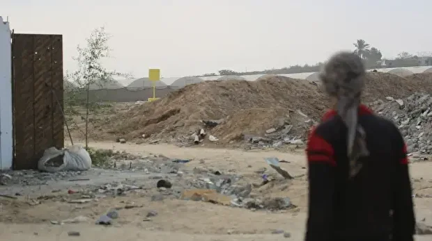 ایک فلسطینی شخص غزہ میں اسرائیلی فوج کی جانب سے پیلی لکیر کی نشاندہی کے لیے رکھے گئے بلاکس کو دیکھ رہا ہے۔ 