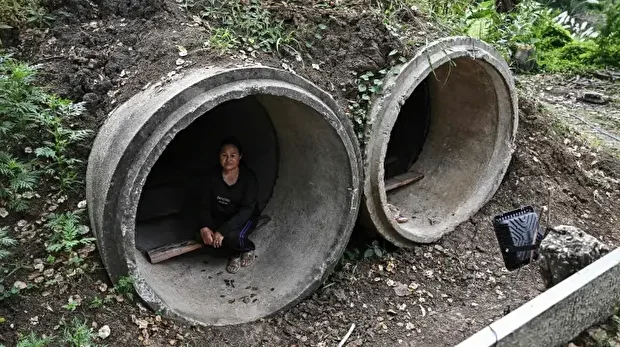 تھائی لینڈ میں ایک خاتون حملوں کے دوران ایک بنکر میں پناہ لیے ہوئے ہیں۔ 