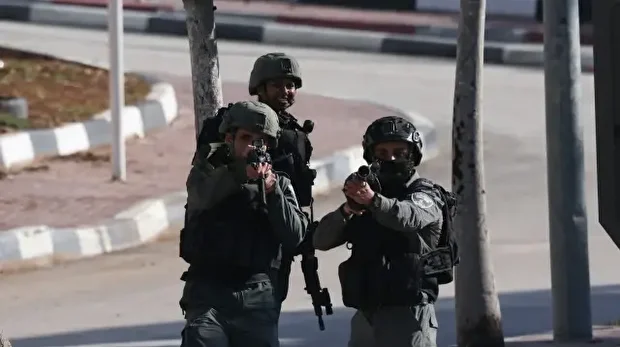 Les forces de sécurité israéliennes pointent leurs armes sur des citoyens palestiniens après avoir bouclé le quartier et les avoir empêchés de rejoindre leurs domiciles, dans la ville de Hébron, en Cisjordanie occupée, le 10 décembre 2025.