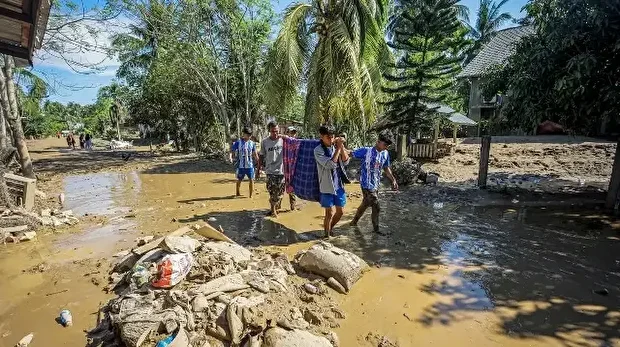 Des villageois évacuent un habitant malade pour l'emmener à l'hôpital le plus proche à Bireuen, dans la province d'Aceh, le 29 novembre 2025, à la suite des inondations soudaines et des glissements de terrain qui ont frappé le nord de Sumatra.