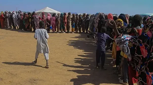 Des femmes soudanaises qui ont fui El-Fasher font la queue pour recevoir de l'aide humanitaire au camp de déplacés d'Al-Afad, dans la ville d'Al-Dabba, au nord du Soudan, le 25 novembre 2025.
