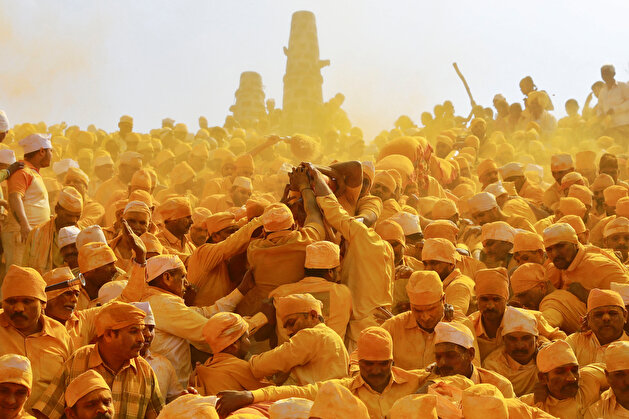 Devotees throw turmeric powder as an offering to the shepherd god Khandoba as others carry a palanquin during 'Somvati Amavasya' at a temple in Jejuri