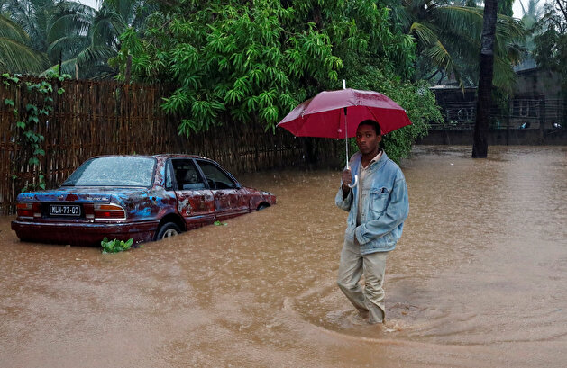People walk down a flooded street in the aftermath of the Cyclone Kenneth in Pemba