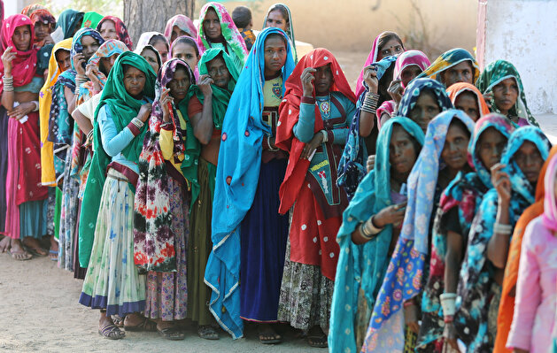 People wait to cast their vote at a polling station at Sirohi
