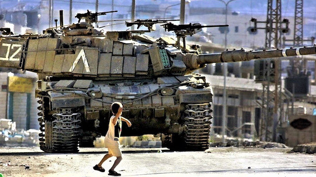Filistinli bir çocuk, İkinci İntifada sırasında Faris Odeh'in ikonik görüntüsüne çok benzer şekilde İsrail Savunma Kuvvetleri'ne ait bir tanka taş atıyor.