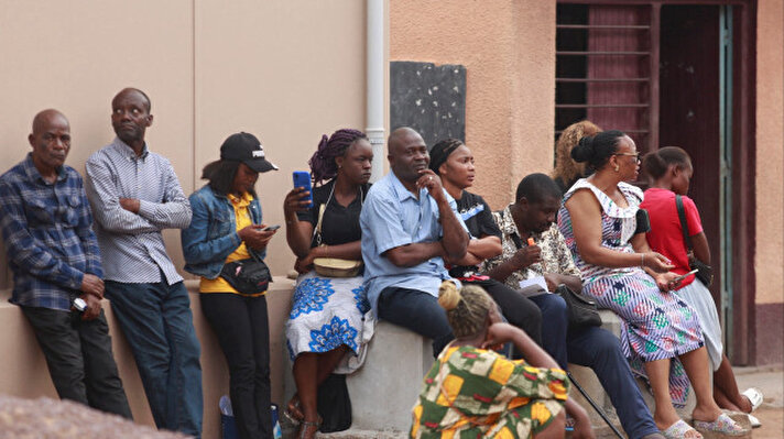 <p>Des personnes attendent devant un bureau en RDC.</p>