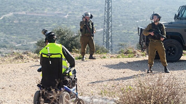 Eski İsrail Başbakanı Ariel Şaron'un, 2000 yılında Mescid-i Aksa'ya girişini protesto etmek için Batı Şeria'nın Ramallah kentinde düzenlenen gösterilere katılan ve İsrail askerlerinin açtığı ateş sonucu yaralanarak sakat kalan 34 yaşındaki Filistinli Bernat, tekerlekli sandalyesinde İsrail'in işlediği suçları ve ihlalleri kayıt altına almaya çalışıyor. 