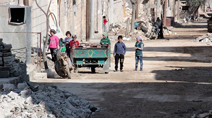 Children stand on a damaged street in Al-Bab district of Aleppo, Syria.