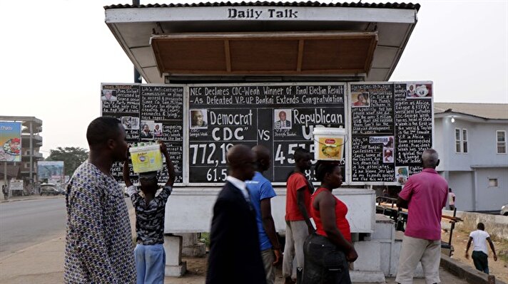 Liberian people read news written with chalk on a blackboard in Monrovia, Liberia on January 3, 2018.

