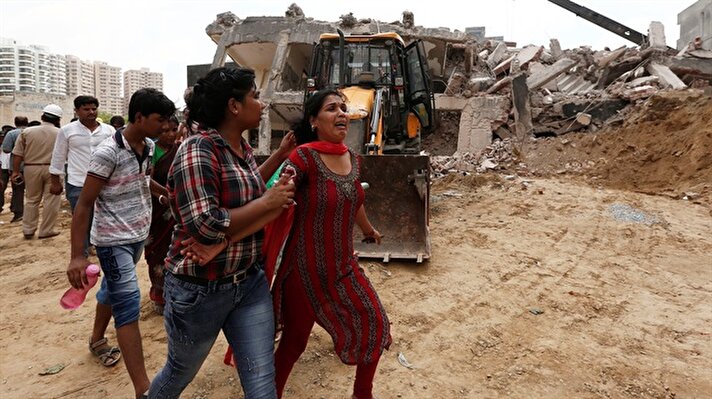 A woman, whose husband is trapped under the rubble, cries at the site of a collapsed residential building at Shah Beri village in Greater Noida, India.