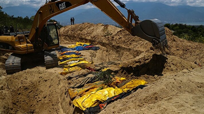 Endonezya askerleri, deprem ve tsunamide hayatını kaybedenlerin naaşlarını Poboya'da kazılan toplu mezarlara defnediyor.
