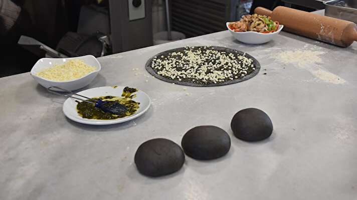 Karşıyaka'da bulunan bir işletmede kafa kafaya veren şefler, deniz ürünlerinin kullanıldığı 'siyah hamurlu pizza' üretmeye karar verdi. 