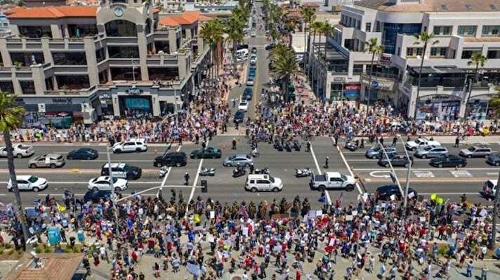 Kaliforniya'nın Orange bölgesindeki plajların kapatılmasını protesto için Huntington Plajı'na yürüyen binlerce kişinin sokaklarda yan yana dip dibe duran görüntüleri, hem ABD  hem dünyada şok etkisi yarattı.  

