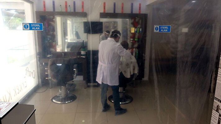  Trabzon'un koronavirüs tedbirleri kapsamında müşterilerinin oturacağı koltukları naylonla kapatan Mustafa Kılıç, steril alan oluşturarak saç tıraşı yapıyor. 