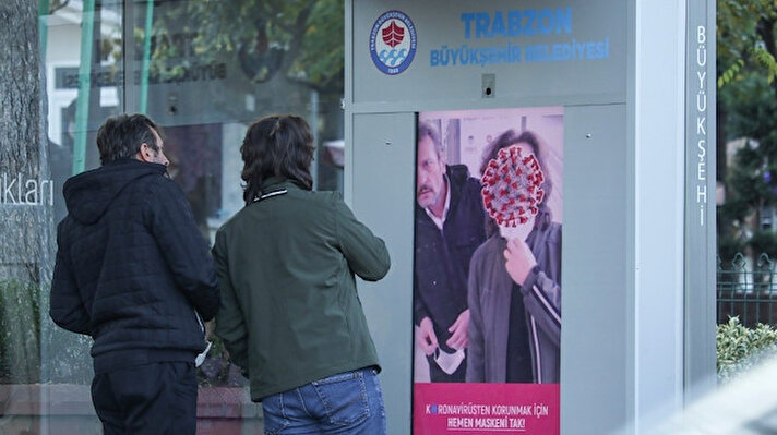 Dijital ekranda yüzlerinin koronavirüse dönüştüğünü gören vatandaşlar, kısa süren şaşkınlıklarının ardından maskelerini takarak durumdan kurtulmaya çalışıyorlar. 
