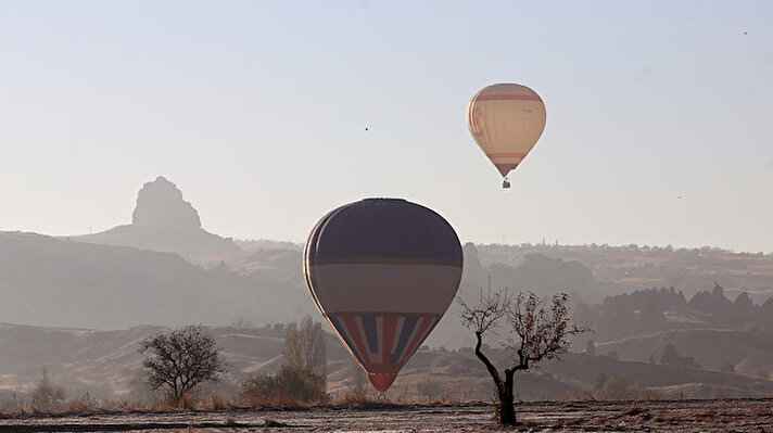 Türkiye'nin önemli turizm merkezlerinden Kapadokya bölgesinde etkili olan sis, sıcak hava balonlarıyla güzel görüntü oluşturdu.