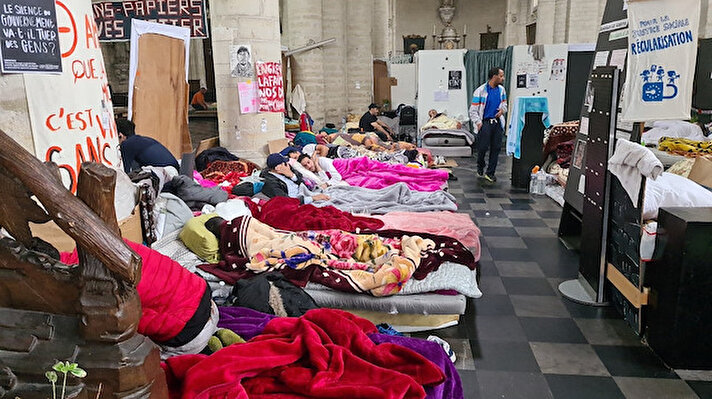 göçmenlerin seslerini duyurabilmek için başlattığı açlık grevi 29. gününü geride bıraktı.
Belçika’nın başkenti Brüksel’in tarihi St. Catherine Meydanı’nda yer alan Beguinage Kilisesi’nde yaklaşık 250 kaçak göçmenin, ülkede oturum hakkı alabilmek için seslerini duyurma çabası sürüyor. Brüksel’de oturum hakkı için yaptıkları başvurulara cevap alamayan göçmenlerin kilisedeki açlık grevi 29. gününü geride bıraktı. Günlerdir açlıktan bitap düşen göçmenlerin sağlık durumu ise giderek kötüleşiyor. Çoğunluğu uzun yıllardan beri Belçika’da bulunan ve "kağıtsızlar" olarak adlandırılan göçmenler, hiçbir siyasinin inisiyatif alarak kendilerine destek olmadığını, tek isteklerinin herkes gibi normal bir hayata kavuşmak olduğunu söylüyor.