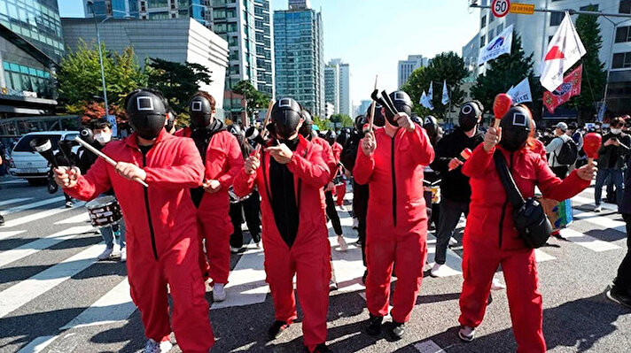 Dünya genelinde izlenme rekorları kıran “Squid Game” adlı dizi çekildiği ülkedeki işçileri sokaklara döktü. Güney Kore’de dizinin karakterleri gibi giyinen on binlerce işçi ülke genelinde protesto düzenledi.<br><br>